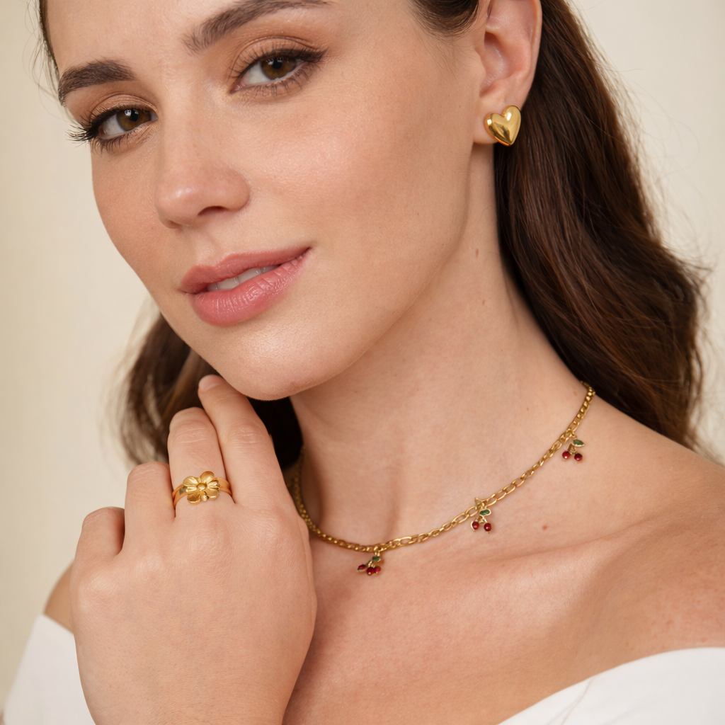 Gold plated jewellery UAE model wearing heart earrings, flower ring, cherry necklace and bracelet