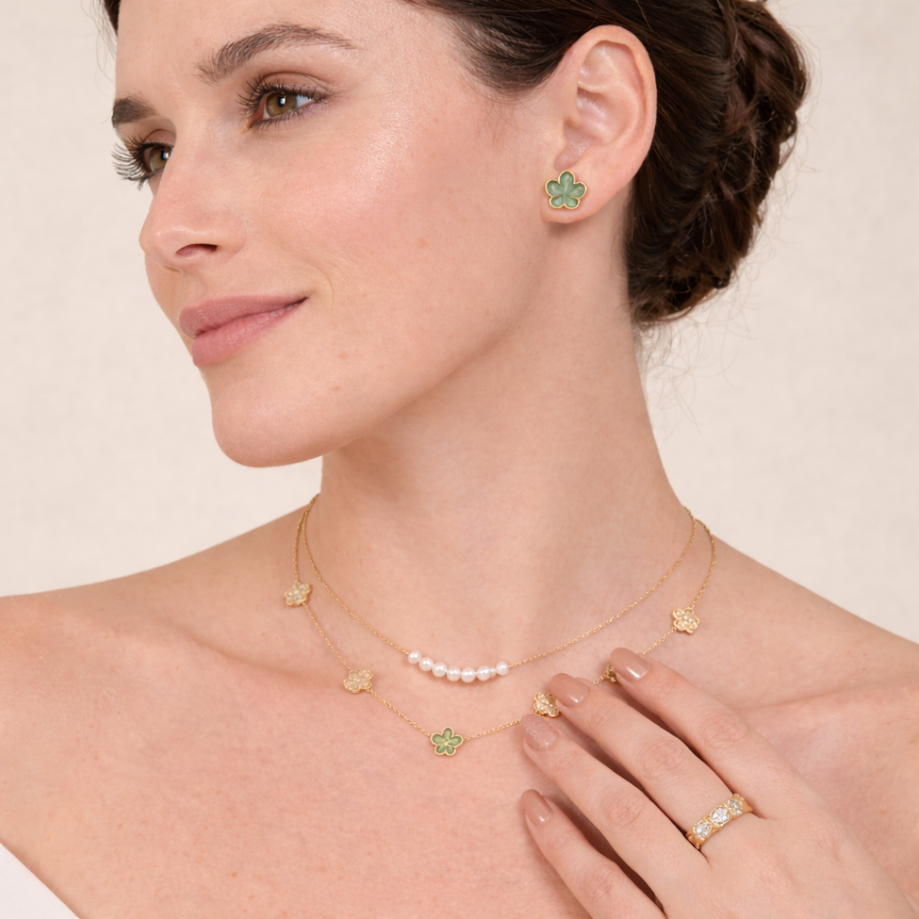 Elegant woman wearing gold plated jewellery in UAE with layered necklace, clover earrings, pearl necklace, and gold ring