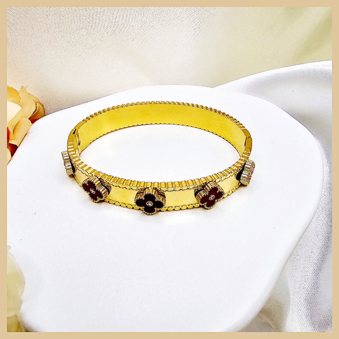 Gold bracelet with embedded stones on a white cushion