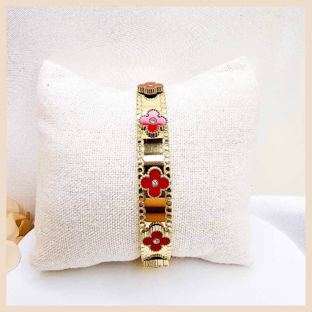 Gold bracelet with red floral designs on a white pillow