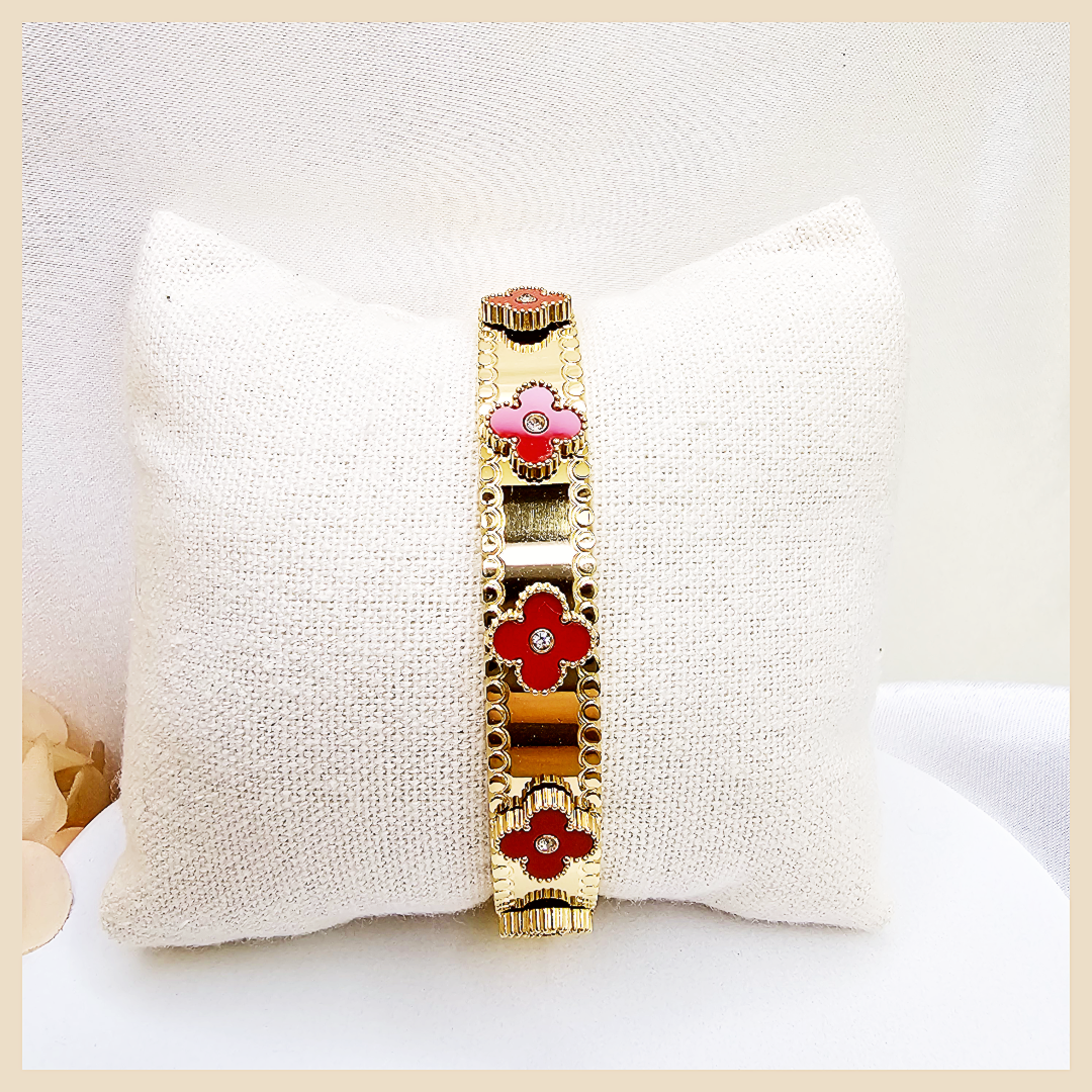 Gold bracelet with red floral designs on a white pillow