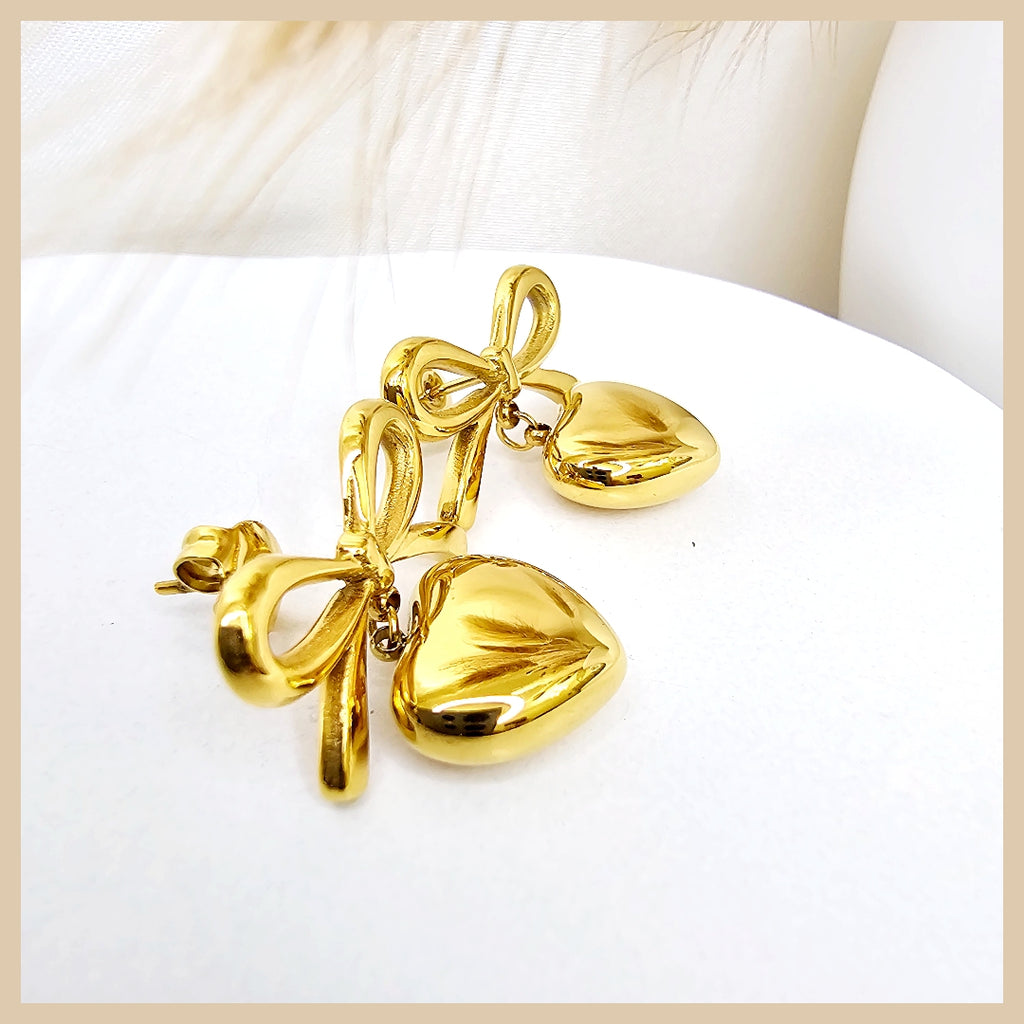 Elegant bow heart earrings in gold plating, offering a polished and feminine look ideal for confident everyday wear or thoughtful gifting.