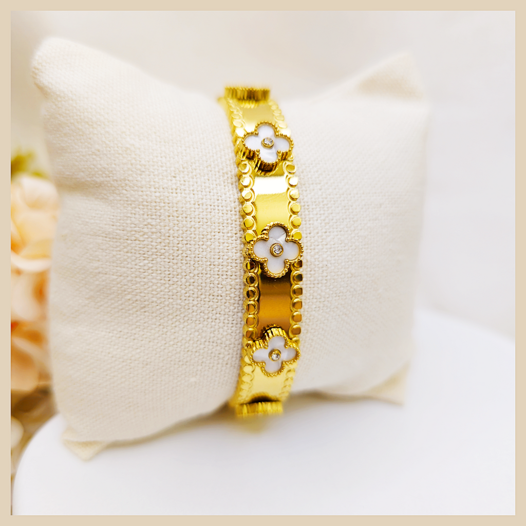 Gold bracelet with floral designs on a white cushion