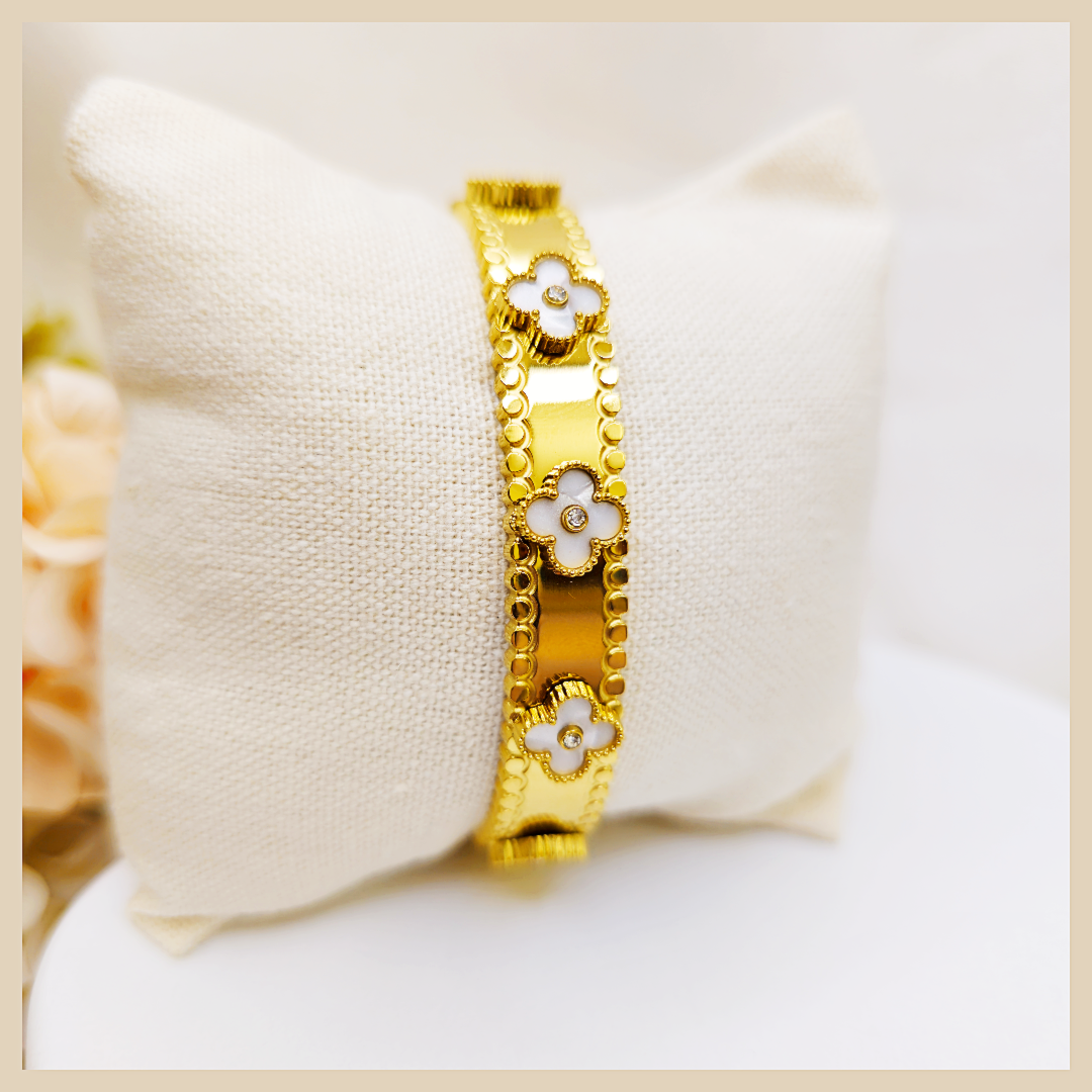 Gold bracelet with floral designs on a white cushion