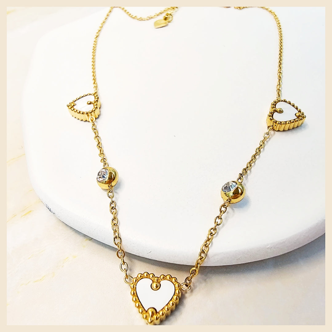 Gold necklace with heart-shaped pendants on a white background