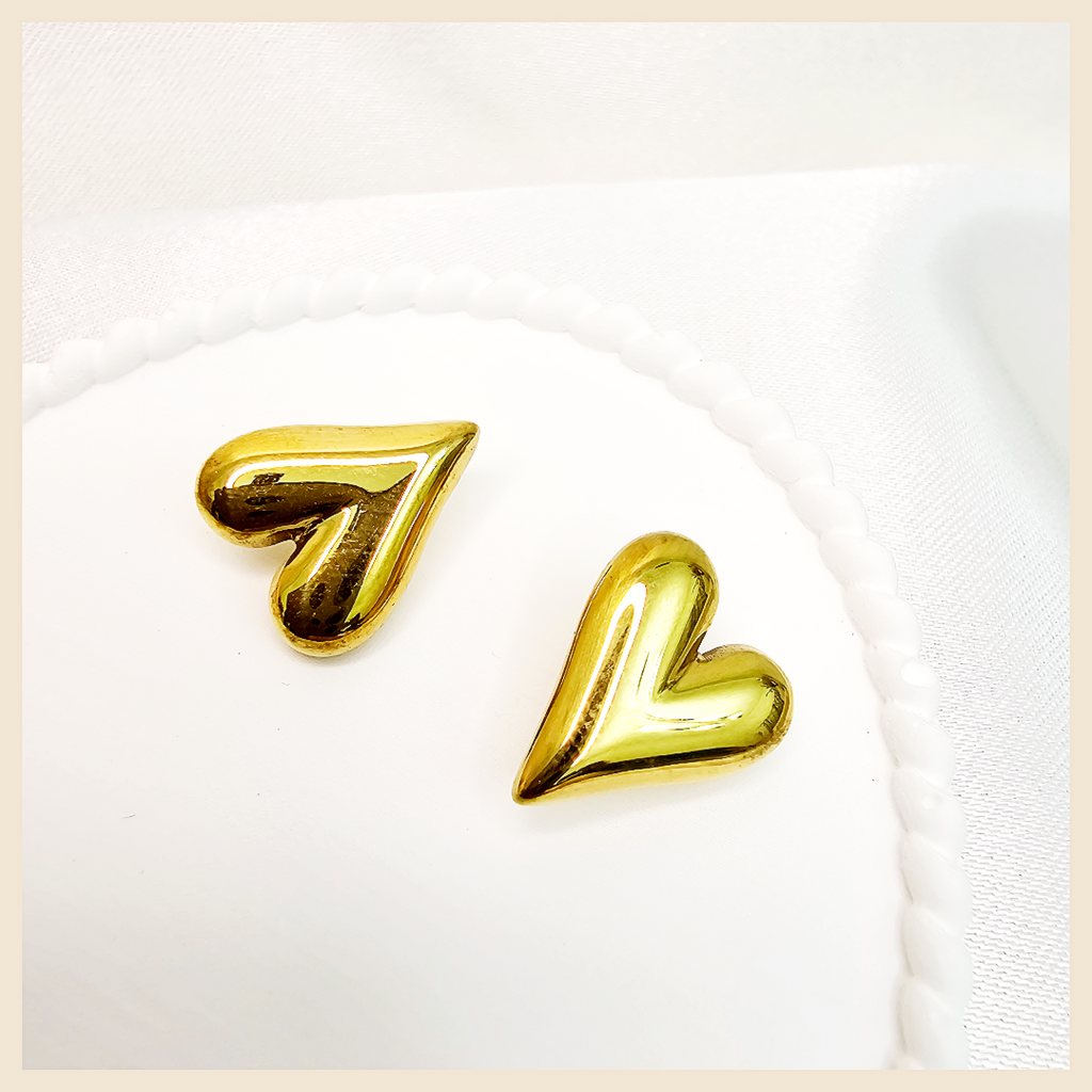 Gold tone dangling heart earrings with a soft shine, perfect for women who appreciate refined beauty and feminine charm.