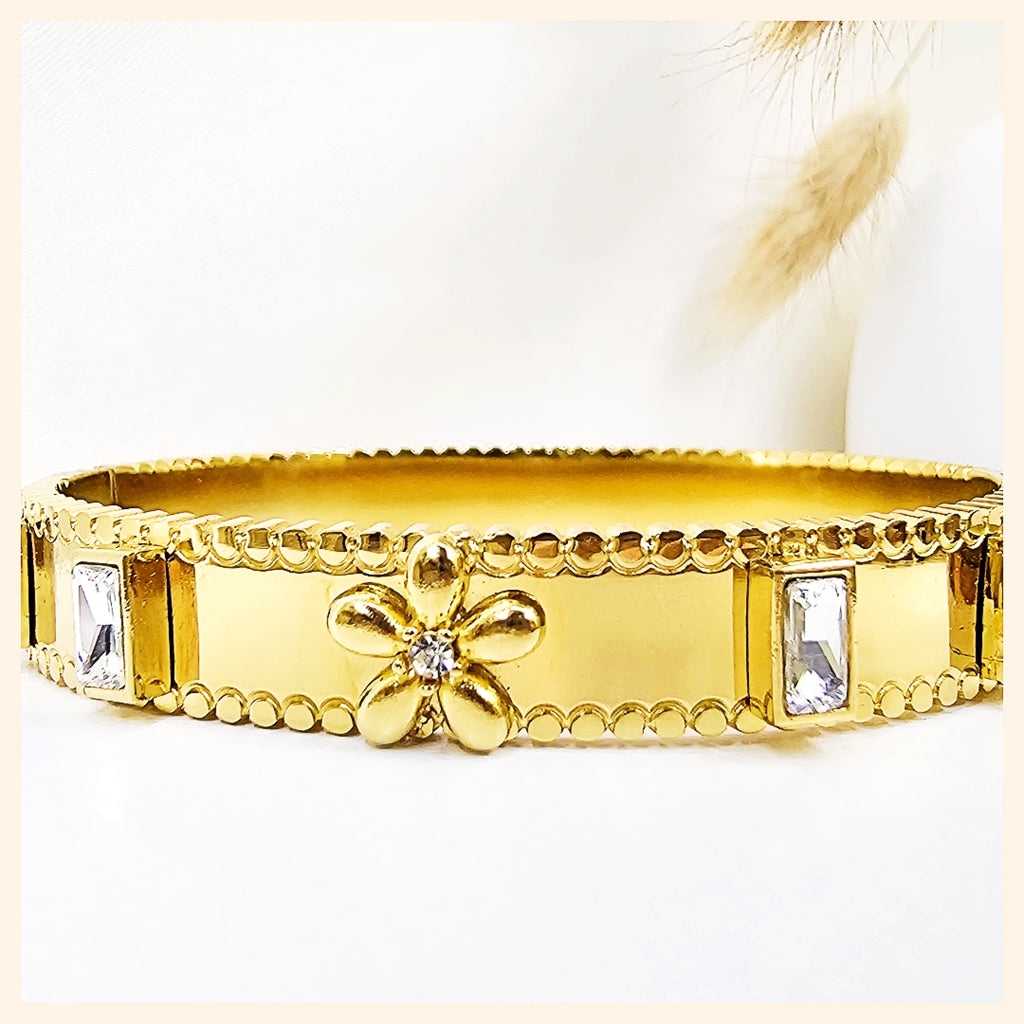 Jemi flower and heart bangle in 18K gold plating, designed for unisex wear with a refined silhouette that suits modern luxury style in the UAE.