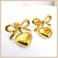 Luxury bow heart earrings in gold, created for women who enjoy expressive jewellery that still reflects trust, exclusivity, and modern sophistication.